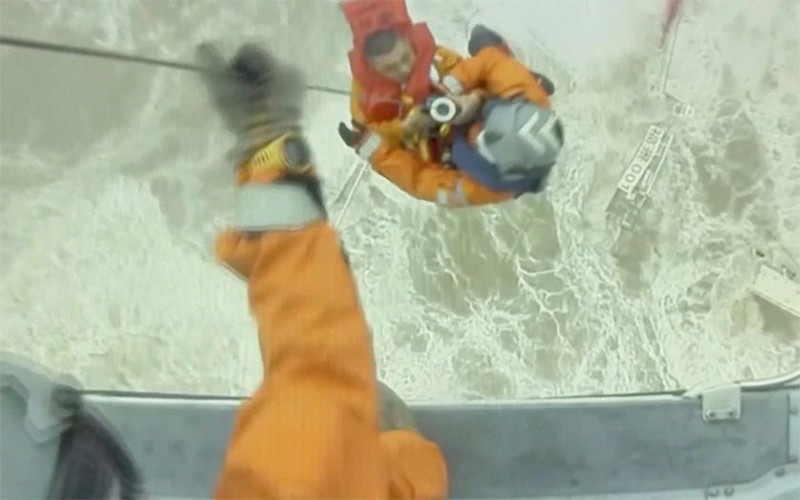 Nhân viên cứu nạn hỗ trợ thành viên thủy thủ đoàn lên trực thăng. (Ảnh: Reuters)