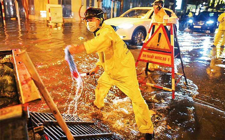 Công nhân Xí nghiệp thoát nước số 1, Công ty TNHH một thành viên Thoát nước Hà Nội ứng trực tại một điểm úng ngập trên địa bàn quận Hoàn Kiếm. (Ảnh: THÀNH ĐẠT)