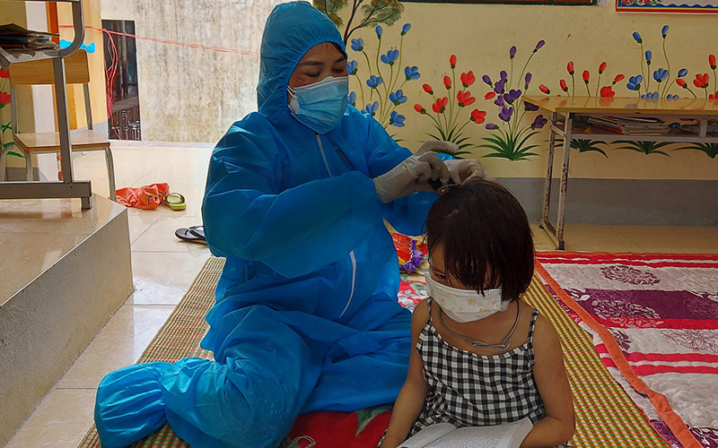 Giáo viên Trường Phổ thông dân tộc bán trú Tiểu học Thuận Hòa giúp đỡ học sinh trong khu cách ly. Ảnh: Nguyễn Thảo