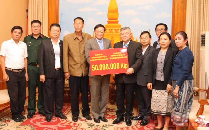 Đại sứ Việt Nam tại Lào Nguyễn Bá Hùng (thứ 5 từ trái qua) trao số tiền ủng hộ Lào, chiều 26-10.