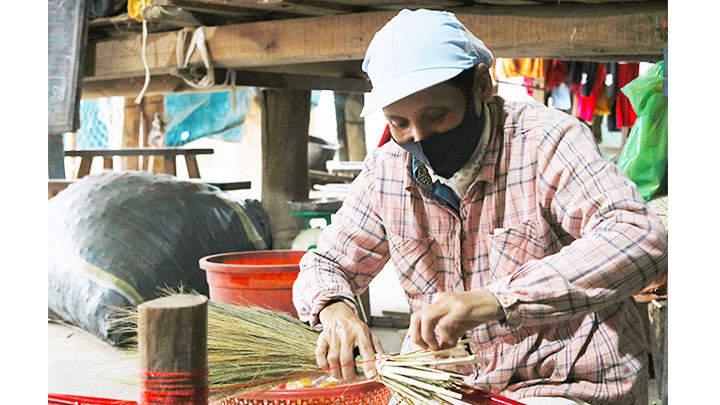 Cô Trần Thị Trinh đang hoàn tất công đoạn buộc chổi vào cán.