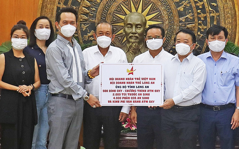 Đồng chí Trương Hòa Bình (thứ 4 từ trái sang) chứng kiến lễ trao vật tư y tế, nhu yếu phẩm và kinh phí hỗ trợ Long An chống dịch.