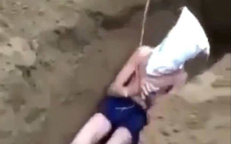 Nam thanh niên bị đẩy xuống hố, sau đó nhóm người dùng xẻng lấp đất. (Ảnh cắt từ video)