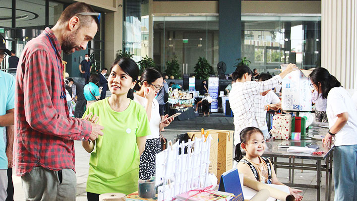 Thu Thảo đang giới thiệu với một người nước ngoài sinh sống trên địa bàn các sản phẩm làm từ rác tái chế.