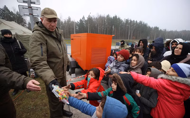 Những người di cư nhận đồ cứu trợ nhân đạo tại khu vực biên giới Belarus-Ba Lan, tháng 11/2021. (Ảnh: Reuters)