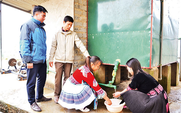 Thầy giáo Vũ Xuân Quế bên hệ thống bếp đun nước nóng bằng công nghệ ủ trấu, giúp hàng trăm học sinh Trường THCS và THPT Bát Xát có nước nóng sử dụng trong mùa đông giá rét.