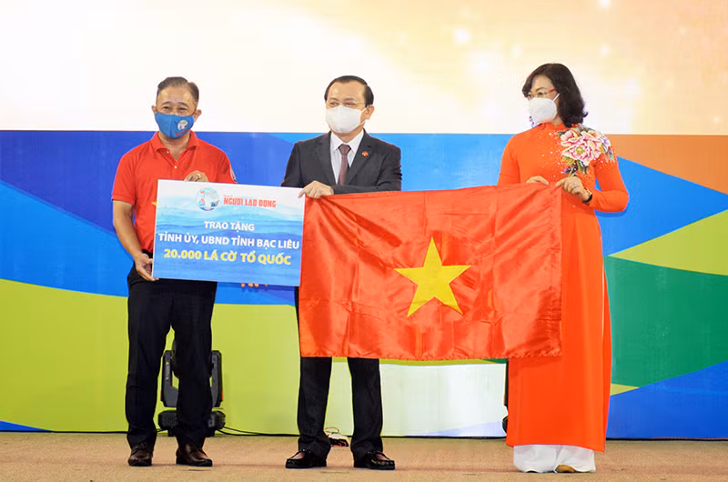 Bà Phan Thị Thắng, Phó Chủ tịch UBND TP Hồ Chí Minh và ông Bùi Thanh Liêm (bìa trái), Phó Tổng Biên tập Báo Người Lao Động, trao cờ Tổ quốc và bảng tượng trưng 20.000 lá cờ cho ông Lê Tấn Cận, Phó Chủ tịch UBND tỉnh Bạc Liêu.