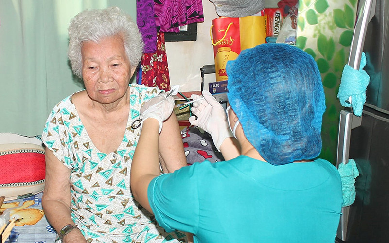 Tiêm vaccine tại nhà cho người già yếu, di chuyển khó khăn ở quận 10, Thành phố Hồ Chí Minh trong dịp Tết Nguyên đán 2022.