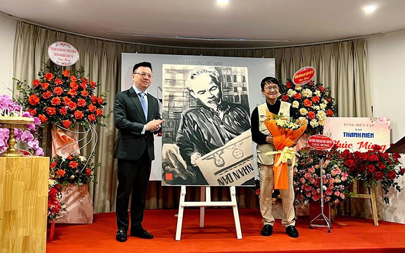 Đồng chí Lê Quốc Minh thay mặt Hội Nhà báo Việt Nam nhận bức vẽ “Bác Hồ đọc Báo Nhân Dân” do tác giả Huỳnh Dũng Nhân trao tặng.