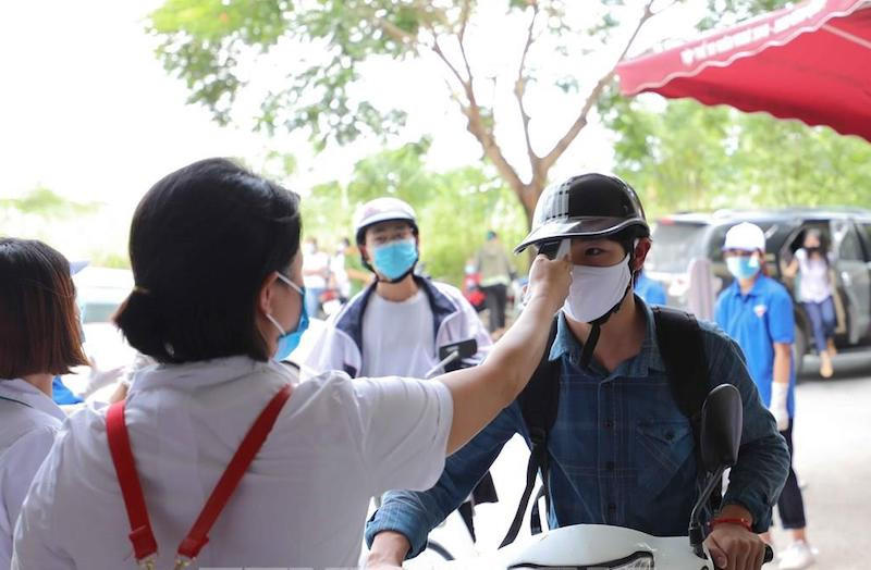 Cán bộ y tế kiêm tra thân nhiệt của thí sinh tham dự Kỳ thi tốt nghiệp THPT 2020 tại Điểm thi Trường THCS Nam Từ Liêm (Cầu Giấy, Hà Nội) chiều 8-8 (Ảnh: THANH TÙNG)
