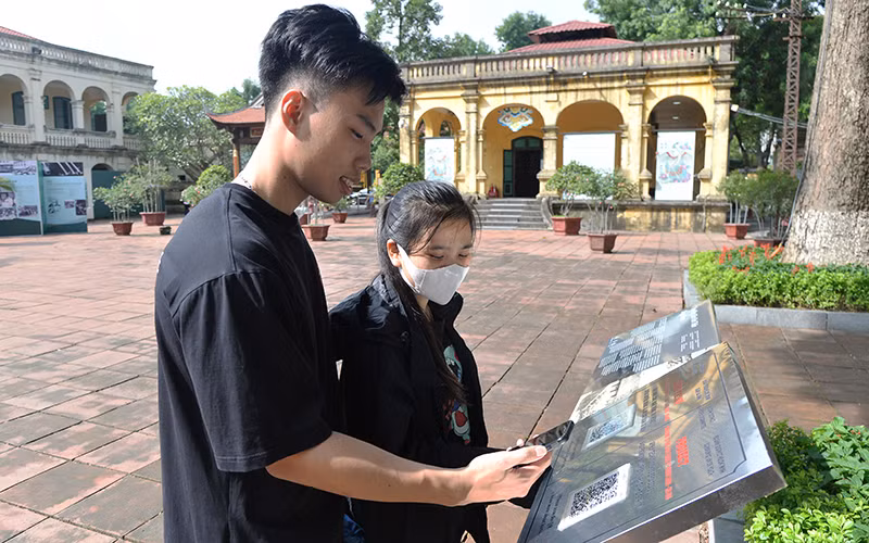 Du khách quét mã QR để tìm hiểu thông tin tại Di sản văn hóa thế giới Hoàng thành Thăng Long (Hà Nội). Ảnh: Bảo Trinh