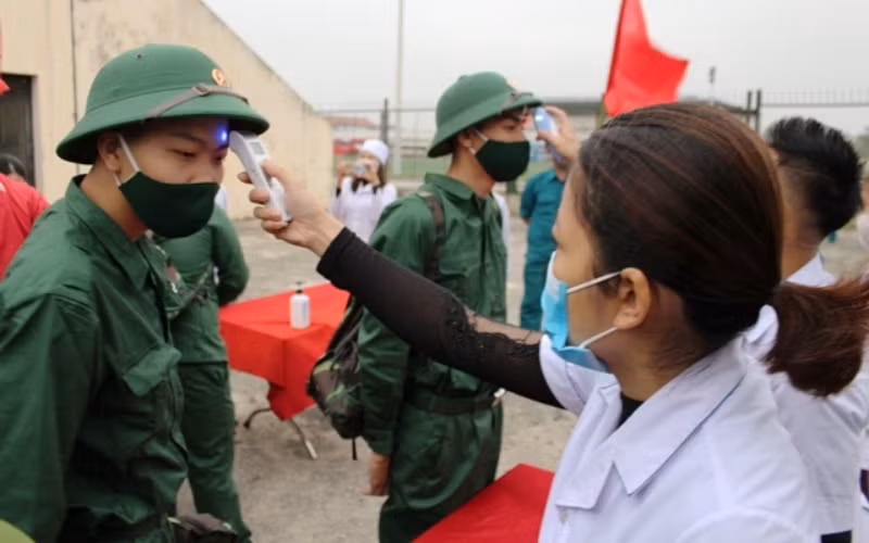 Nhân viên y tế huyện Quảng Xương kiểm tra thân nhiệt các tân binh trước lễ giao, nhận quân năm 2021.