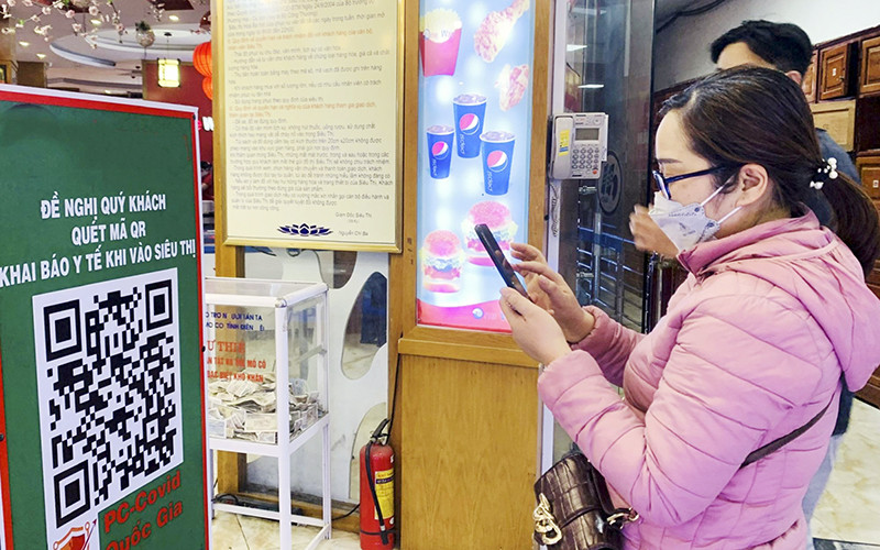 Người dân sử dụng điện thoại thông minh quét mã QR tại các địa điểm công cộng. (Ảnh MINH THÚY)