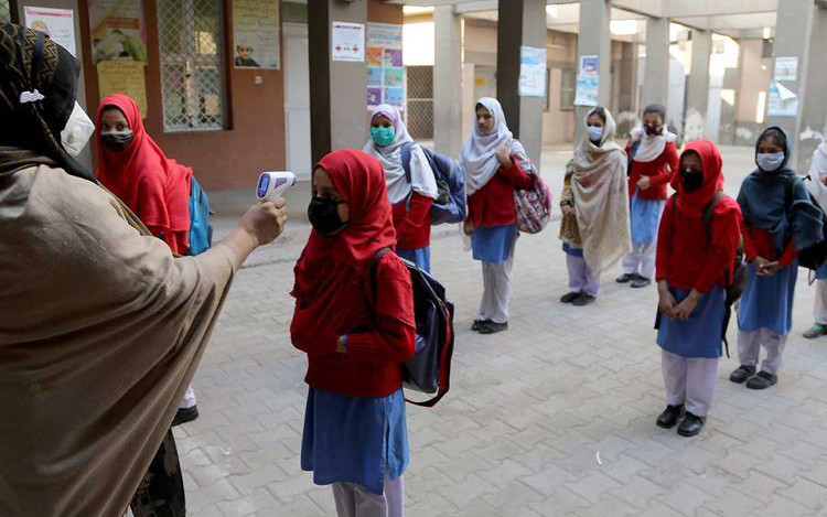 Kiểm tra thân nhiệt phòng lây nhiễm Covid-19 tại một trường học ở Pa-ki-xtan. Ảnh AP 