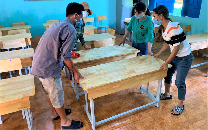 Giáo viên và phụ huynh Trường tiểu học Bùi Thị Xuân, xã vùng sâu Ea M’Droh, huyện Cư M’gar chuẩn bị bàn ghế đón học sinh đến trường học tập.