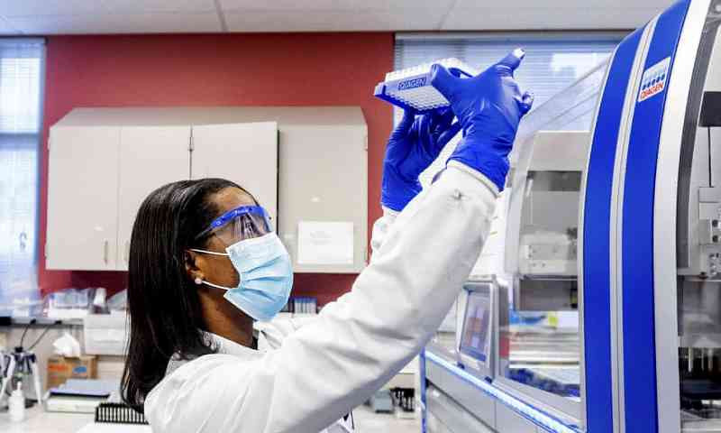 Một nhà khoa học quan sát các mẫu xét nghiệm lấy từ người nghi mắc Covid-19. (Ảnh: AP)