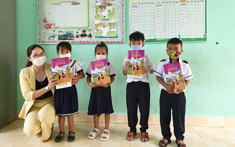 Cô Doãn Kim Huế, Hiệu trường Trường Tiểu học Cao Bá Quát trao sách giáo dục địa phương và tập vở do Báo Nhân Dân vận động cho các em học sinh. (Ảnh: Phúc Thắng)