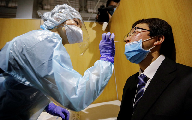 Một hành khách được lấy mẫu xét nghiệm trước khi ra nước ngoài tại sân bay Narita (Ảnh: REUTERS)