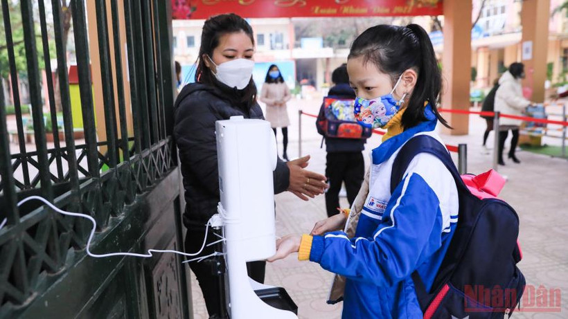 Các giáo viên trường tiểu học tại huyện Hoài Đức nhắc các em học sinh sát khuẩn tay, kiểm tra thân nhiệt trước khi vào học. (Ảnh: DUY LINH)