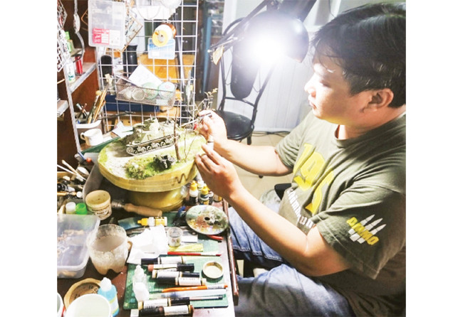 Họa sĩ Lê Xuân Giang bên các tác phẩm sa bàn do anh chế tác.