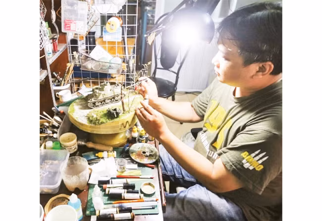 Họa sĩ Lê Xuân Giang bên các tác phẩm sa bàn do anh chế tác.