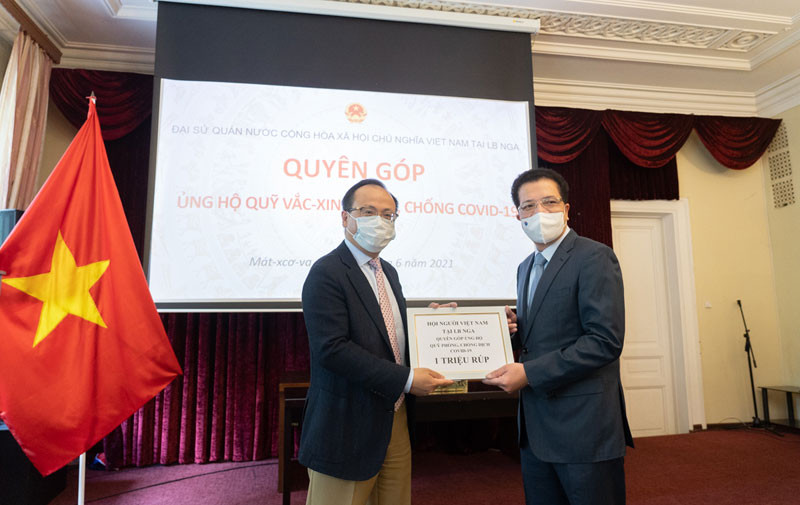 Chủ tịch Hội người Việt Nam tại LB Nga Đỗ Xuân Hoàng (bên trái) trao tượng trưng số tiền ủng hộ phòng, chống dịch Covid-19.