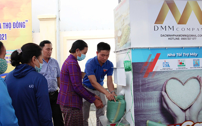 Lê Thanh Hải (ngoài cùng bên phải) hỗ trợ người dân nhận gạo tại cây ATM.