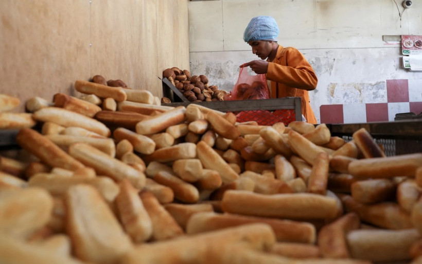 Thợ làm bánh gói những ổ bánh mì vào túi nilon tại 1 tiệm bánh ở Sanaa, Yemen, ngày 1/3/2022. (Ảnh: REUTERS)