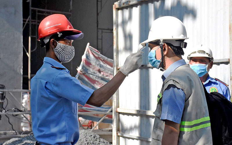 Ðo thân nhiệt cho công nhân khi vào công trường ở Ðà Nẵng.