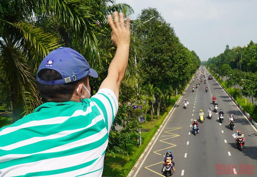 Tác giả vẫy tay chào anh chị em công nhân từ Đồng Nai về quê các tỉnh Tây Nguyên. (Ảnh Phước Tuấn).