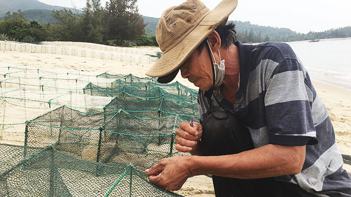 Ngư dân từng mắc bệnh cùi đang gỡ cá.