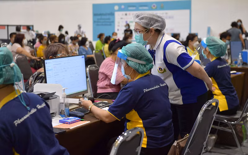 Nhân viên y tế kiểm tra thông tin của người dân tại một điểm tiêm chủng ở Bangkok. (Ảnh: NAM ĐÔNG)