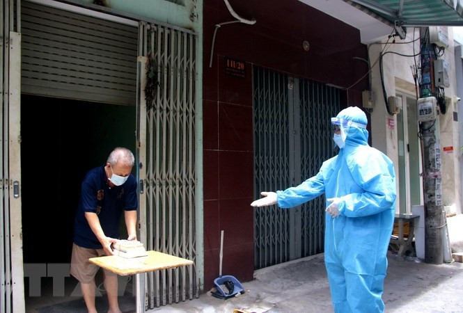 Phát sách cho người dân khu cách ly, phong tỏa trong chương trình “Khép cửa đọc sách”. Ảnh: TTXVN.