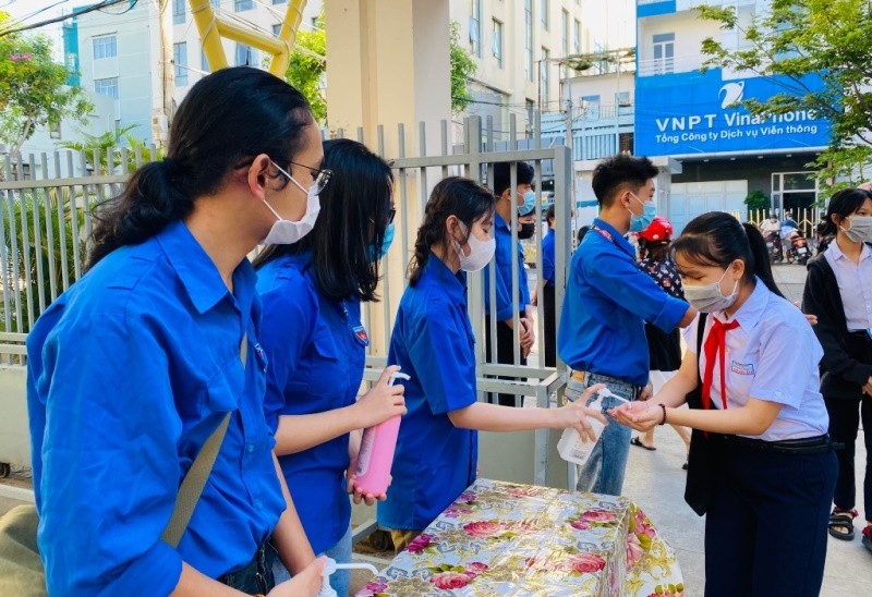 Thanh niên tình nguyện đo thân nhiệt học sinh trước khi vào điểm thi.