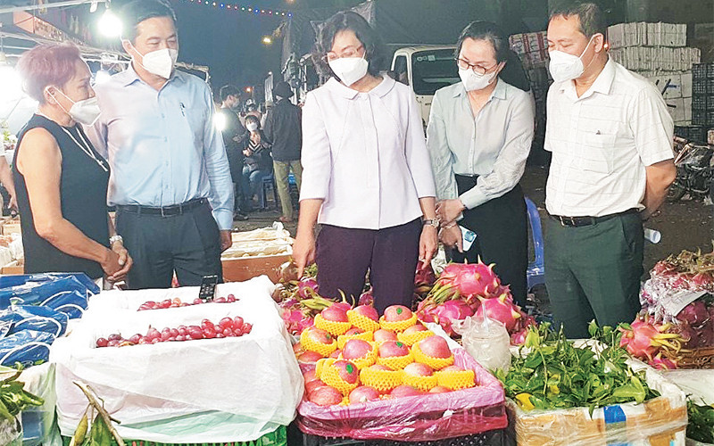 Lực lượng chức năng kiểm tra hoạt động kinh doanh của một gian hàng buôn bán trái cây tại chợ đầu mối nông sản-thực phẩm Thủ Đức. 