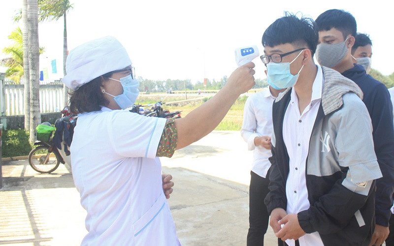Thí sinh Trường THPT Hùng Vương (huyện Thăng Bình) được kiểm tra nhiệt độ khi đến làm thủ tục dự thi.