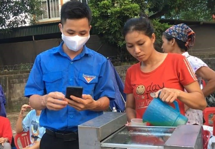 Đề nghị người dân và các hộ gia đình hãy cùng hợp tác và ủng hộ khi các tổ chức, đoàn thể hỗ trợ cài đặt ứng dụng Bluezone. Trong ảnh là tình nguyện viên hướng dẫn cài đặt Bluezone cho người bán nước mía ở Lào Cai.