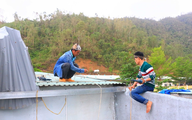 Anh Nguyễn Văn Thuận (bìa trái) sửa mái tôn cho một gia đình.