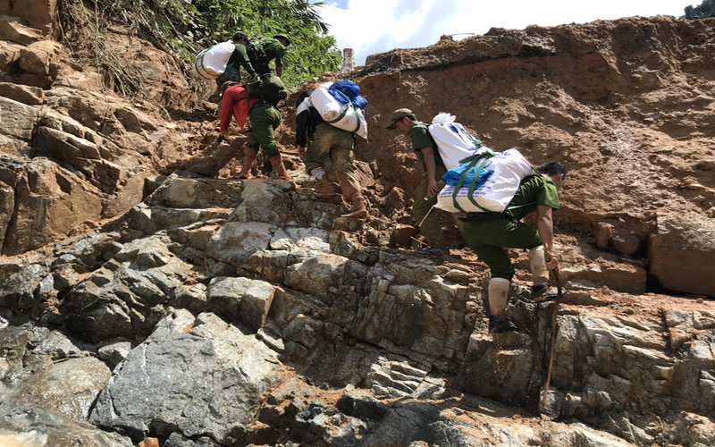 Lực lượng chức gùi hàng hóa vào tiếp tế cho người dân bị cô lập.