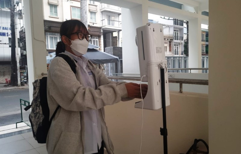 Học sinh khối 10 Trường THPT Bùi Thị Xuân, quận 1, TP Hồ Chí Minh đo thân nhiệt, sát khuẩn trước khi vào trường học.