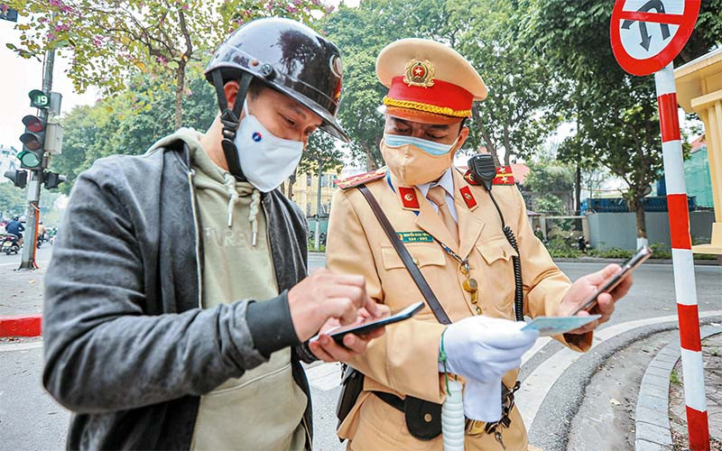 Cán bộ Đội Cảnh sát giao thông số 2 hướng dẫn người dân nộp phạt trực tuyến. (Ảnh NGUYỄN THẮNG)