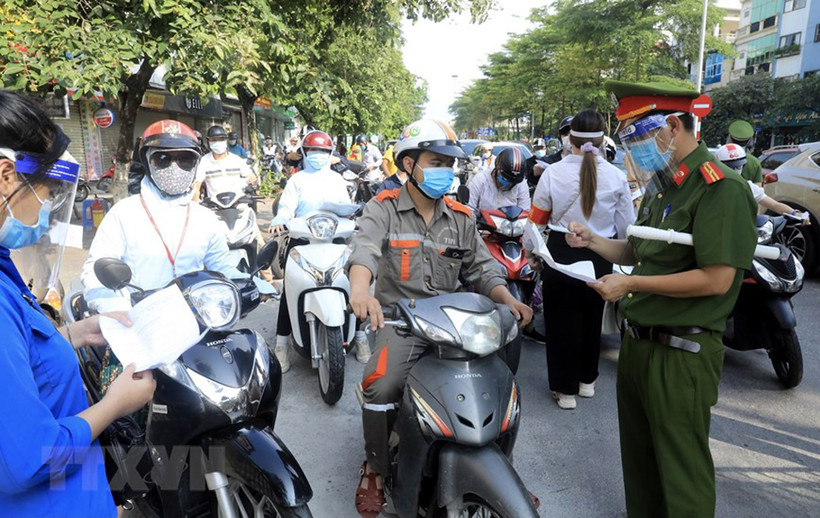 Lực lượng chức năng kiểm tra giấy tờ tùy thân và xác nhận đi làm, ra ngoài của cơ quan với người dân lưu thông trên đường Đào Tấn, Hà Nội, sáng 28/7.