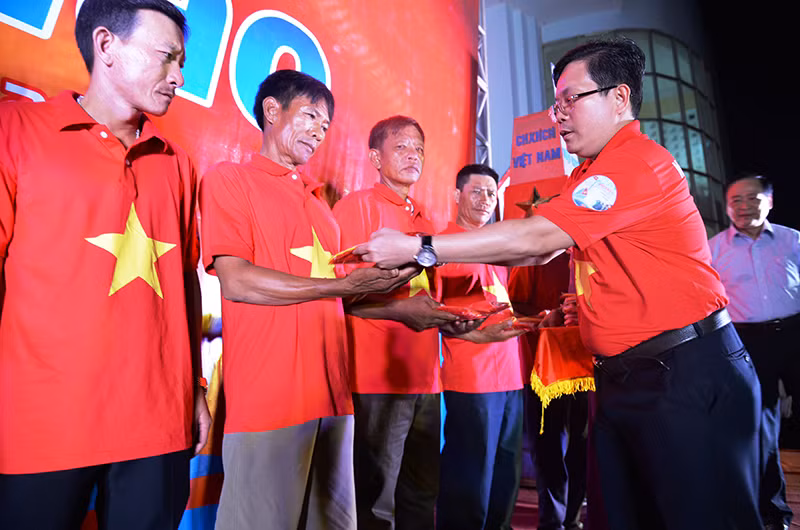 Đồng chí Tô Đình Tuân, Tổng Biên tập Báo Người Lao Động trao cờ cho ngư dân.