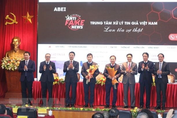 Phó Thủ tướng Vũ Đức Đam và Bộ trưởng Bộ Thông tin và Truyền thông Nguyễn Mạnh Hùng tặng hoa chúc mừng Khai trương Cổng thông tin tiếp nhận phản ánh và công bố tin giả và ra mắt đầu số tiếp nhận phản ánh tin giả 18008108. Ảnh: TTXVN.