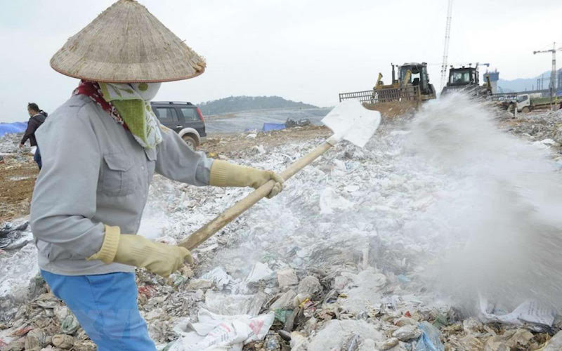 Công nhân Công ty TNHH MTV Môi trường đô thị Hà Nội rắc chế phẩm khử mùi tại bãi rác Nam Sơn. (Ảnh: KHÁNH SƠN)
