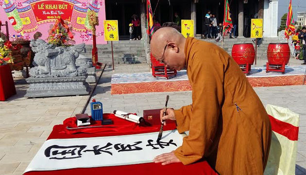 Thượng tọa Thích Quang Tùng khai bút với bức thư pháp bốn chữ “Quốc thái, dân an”. Ảnh chụp Xuân Bính Thân 2016 của NGÔ QUANG DŨNG