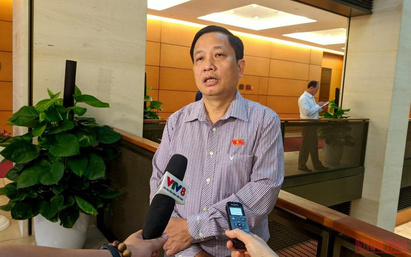 Đại biểu Hà Quốc Trị trao đổi bên hành lang Quốc hội. (Ảnh: TRUNG HƯNG)