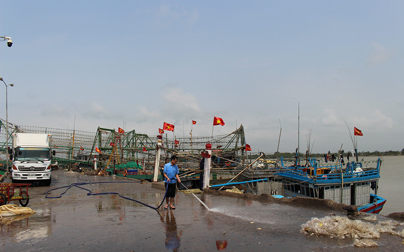 Người lao động làm vệ sinh khu vực tàu cá cập Cảng Hới bốc, dỡ hải sản.