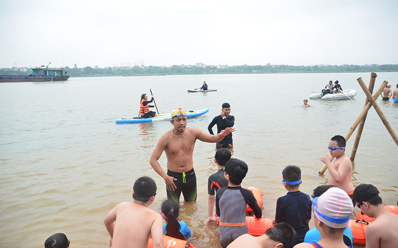 Nguyễn Ngọc Khánh hướng dẫn từng động tác bơi cho các em nhỏ trên sông Hồng.