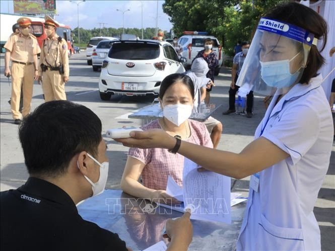 Kiểm tra thân nhiệt tại một chốt kiểm soát dịch ở Hà Nội. Ảnh: TTXVN.